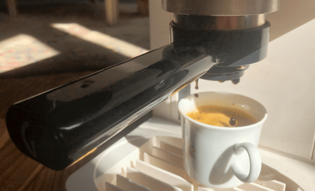 Gros plan d'une tasse d'expresso de chicorée avec mousse sous percolateur en cours de versement